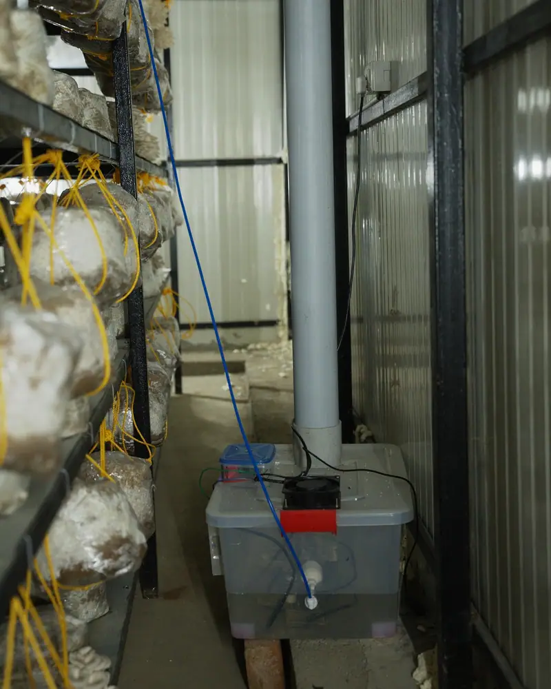 A humidifier unit on the floor at the end of a rack, with its supply pipe